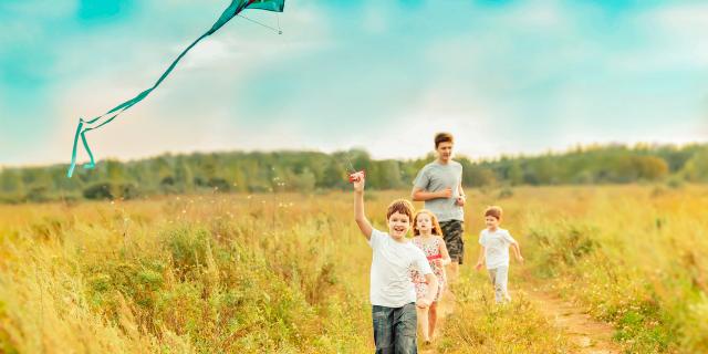 4 enfants courant dans un champ sous un ciel bleu