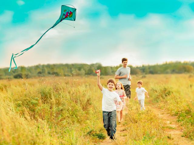 4 enfants courant dans un champ sous un ciel bleu