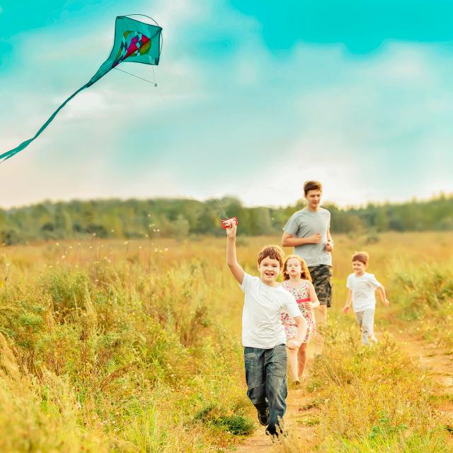 4 enfants courant dans un champ sous un ciel bleu