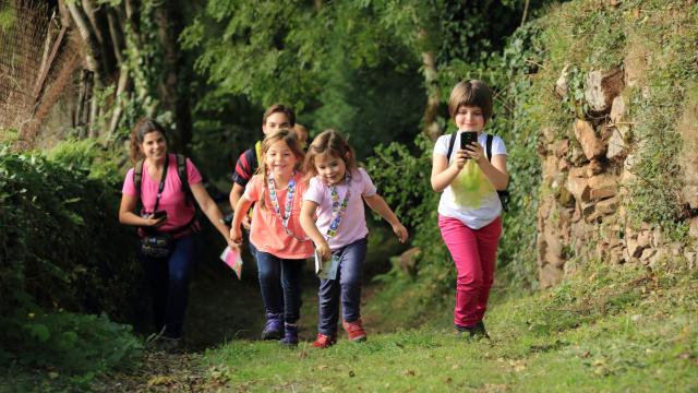 3 enfants et 2 adultes sur un chemin effectuant un parcours Terra Aventura, téléphone en main