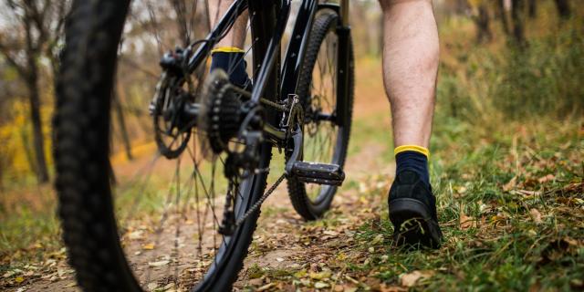 Vue resserrée d'un homme avec son pied sur la pédale d'un VTT dans la campagne