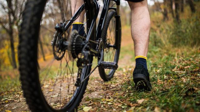 Vue resserrée d'un homme avec son pied sur la pédale d'un VTT dans la campagne