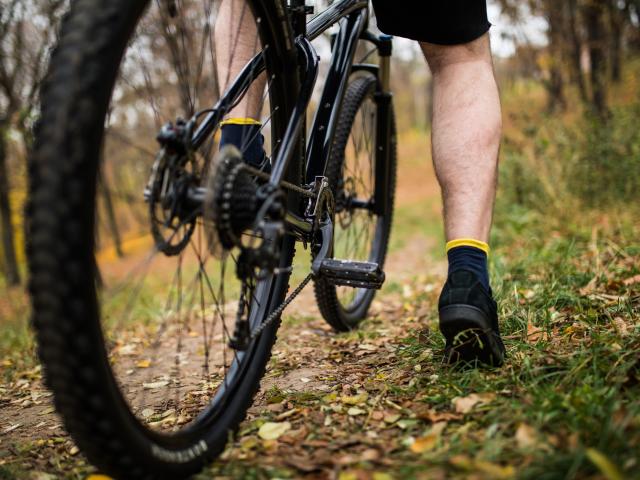 Vue resserrée d'un homme avec son pied sur la pédale d'un VTT dans la campagne