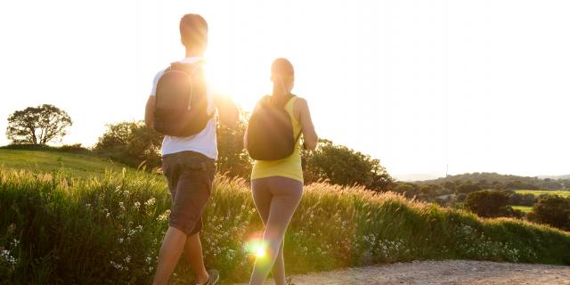 Portrait d'un jeune couple de randonneurs heureux en train de marcher of Happy Young couple on the field in spring