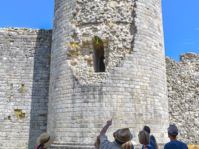 Des visiteurs du Château de Ventadour écoutent les explications de Cédric, le guide du Château. Ils font face à la grande tour, un édifice en pierres de plus de 17 mètres de haut.